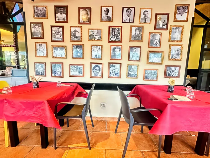 Sala interna di eTrigu con parete di ritratti e tavoli apparecchiati